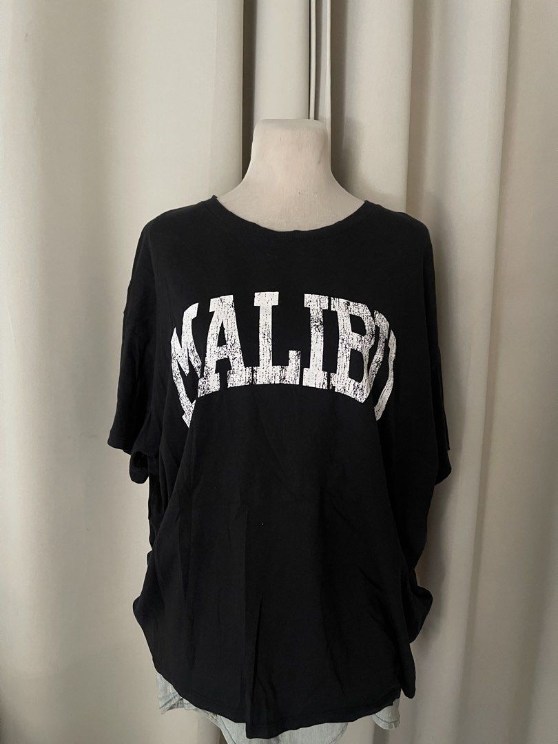 H&M Divided Black Malibu (Category: Shirts) located in Cainta. Submitted by zlove111 (Listing ID 1469620304, Image 1). Description: - Brand/Model: H&M Divided - Color: Black with white distressed 'Malibu' collegiate graphic - Fit: Relaxed, oversized fit with crew neckline - Size: Medium (tag attached) up to xl boxy 23" - Material: Soft and comfortable cotton - Styling: Easy to pair with denim jeans or shorts for a casual streetwear look not faded