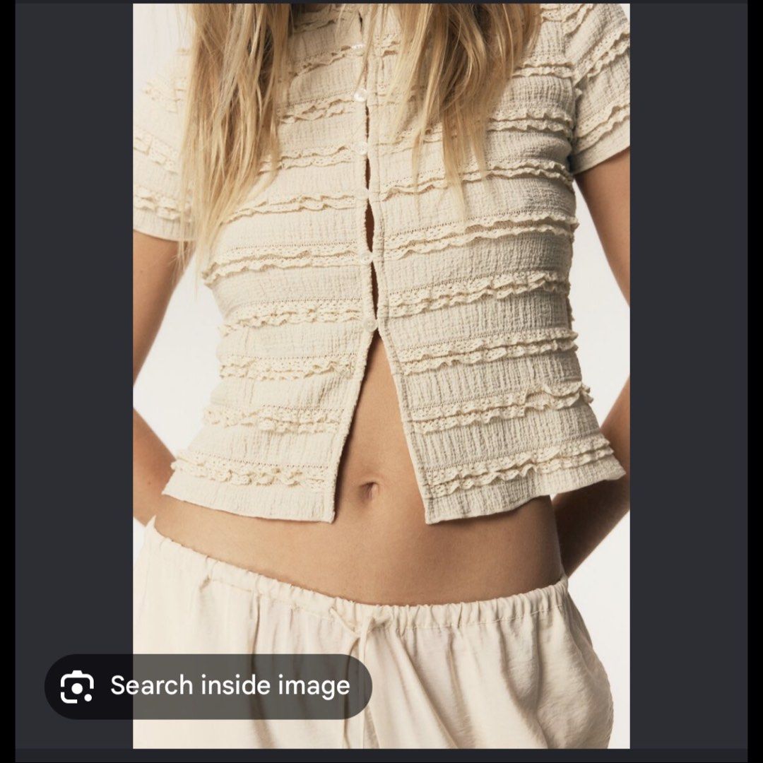 H&M Divided Cream Textured Ruffle Button-Up Top (Category: Blouses) located in Malabon City. Submitted by icooooooo (Listing ID 1469621271, Image 2). Description: - Brand: H&M Divided - Color: Cream - Style: Short sleeve cropped top with round neckline - Details: Textured crinkled fabric, horizontal ruffles, lace trim, and full front button placket with matching buttons - Material: Lightweight - Condition: Clean and well-maintained.