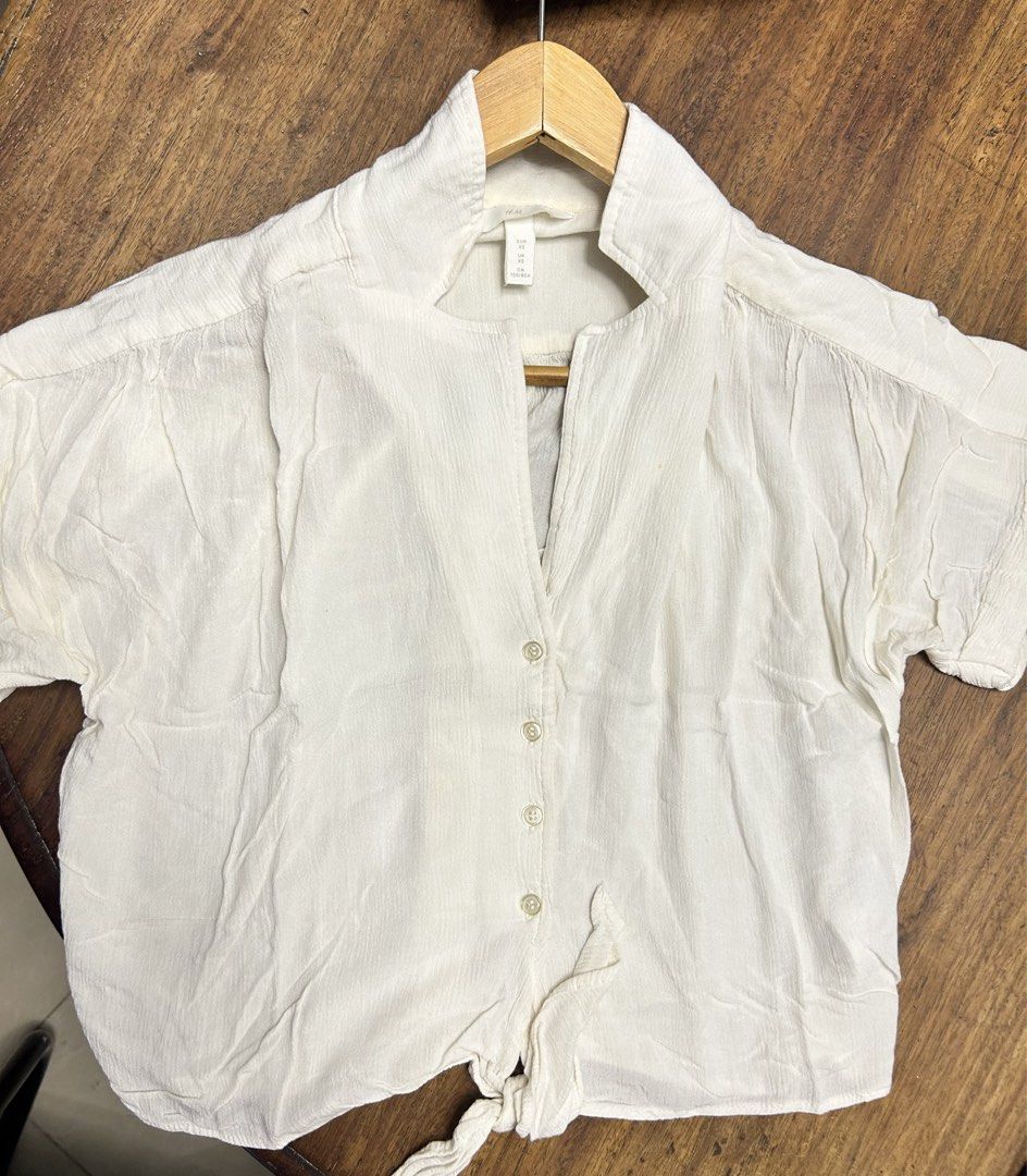H&M Short Sleeve Polo Top (Category: Others Tops) located in Antipolo. Submitted by tshopph (Listing ID 1469714922, Image 1). Description: Breezy and stylish short-sleeve button-up top from H&M. Features a relaxed notched collar, front button closure, and a trendy tie-front hem detail. Made from a lightweight, textured fabric that is perfect for tropical weather, casual outings, or beach trips. Pairs effortlessly with high-waisted shorts, skirts,