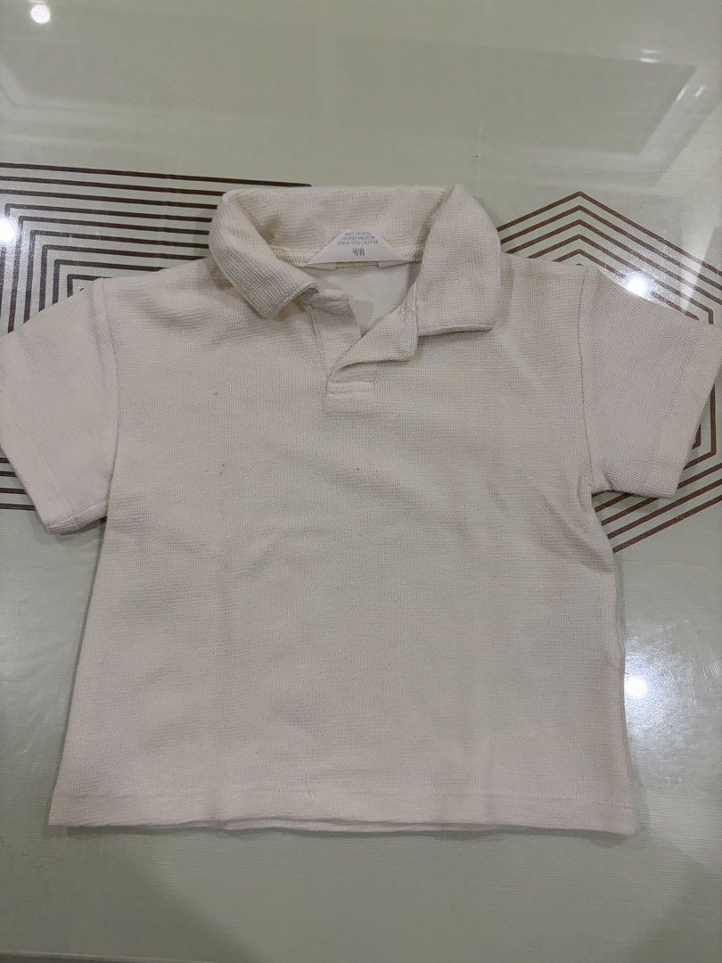 H&M Textured Polo Shirt Off White (Category: Babies & Kids Fashion) located in Las Pinas. Submitted by rcv.preloved (Listing ID 1469680388, Image 1). Description: - Color: Off-white - Material: Waffle knit textured fabric - Design: Classic collar with short button placket - Fit: Short sleeve, casual fit - Versatility: Neutral color goes with everything and is easy to style.