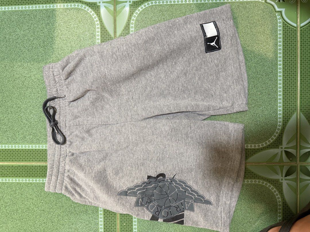 Jordan Grey Sweatshorts with Wings Logo (Category: Shorts) located in Vinzons. Submitted by pongsthrift (Listing ID 1469677690, Image 3). Description: - Authentic Jordan grey cotton fleece shorts - Comfortable elastic waistband with dark grey adjustable drawstring - Bold vertical Jordan branding on the left leg - Nike Swoosh and iconic Air Jordan wings logo on the right leg - Woven jock tag patch near the hem for added detail - Casual and versati