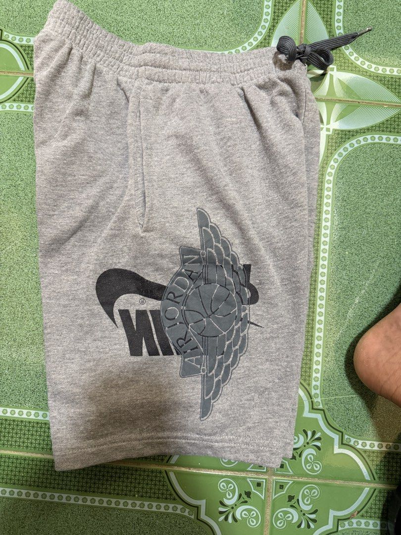 Jordan Grey Sweatshorts with Wings Logo (Category: Shorts) located in Vinzons. Submitted by pongsthrift (Listing ID 1469677690, Image 2). Description: - Authentic Jordan grey cotton fleece shorts - Comfortable elastic waistband with dark grey adjustable drawstring - Bold vertical Jordan branding on the left leg - Nike Swoosh and iconic Air Jordan wings logo on the right leg - Woven jock tag patch near the hem for added detail - Casual and versati