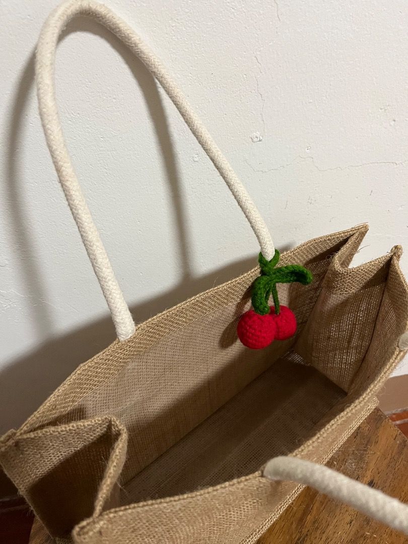 Jute Tote Bag with Crochet Cherry Charm (Category: Tote Bags) located in Cabuyao City. Submitted by rdtrmt (Listing ID 1469666966, Image 3). Description: - Material: Durable neutral brown burlap with soft white fabric handles - Features: Includes a cute handmade crochet cherry charm on the strap - Design: Structured rectangular shape with a flat bottom - Capacity: Roomy interior for all your essentials - Best For: Daily use, grocery runs, and cas