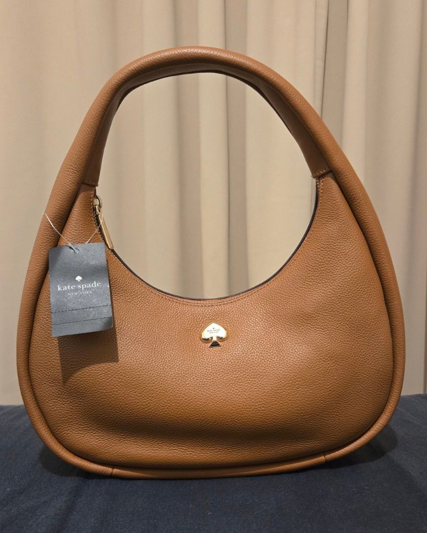 Kate Spade Kayla Crescent Shoulder Bag Warm Ginger (Category: Luxury Bags & Wallets) located in San Juan City. Submitted by paulasfinds (Listing ID 1469713880, Image 1). Description: - Brand: Kate Spade - Style: Kayla Shoulder Bag / Crescent Silhouette - Color: Warm Ginger - Material: Premium pebbled leather - Dimensions: 14" H x 12" L (widest point) x 3.4" W - Handle Drop: 8 inches - Closure: Secure top zip - Interior: Back zip pocket and signat