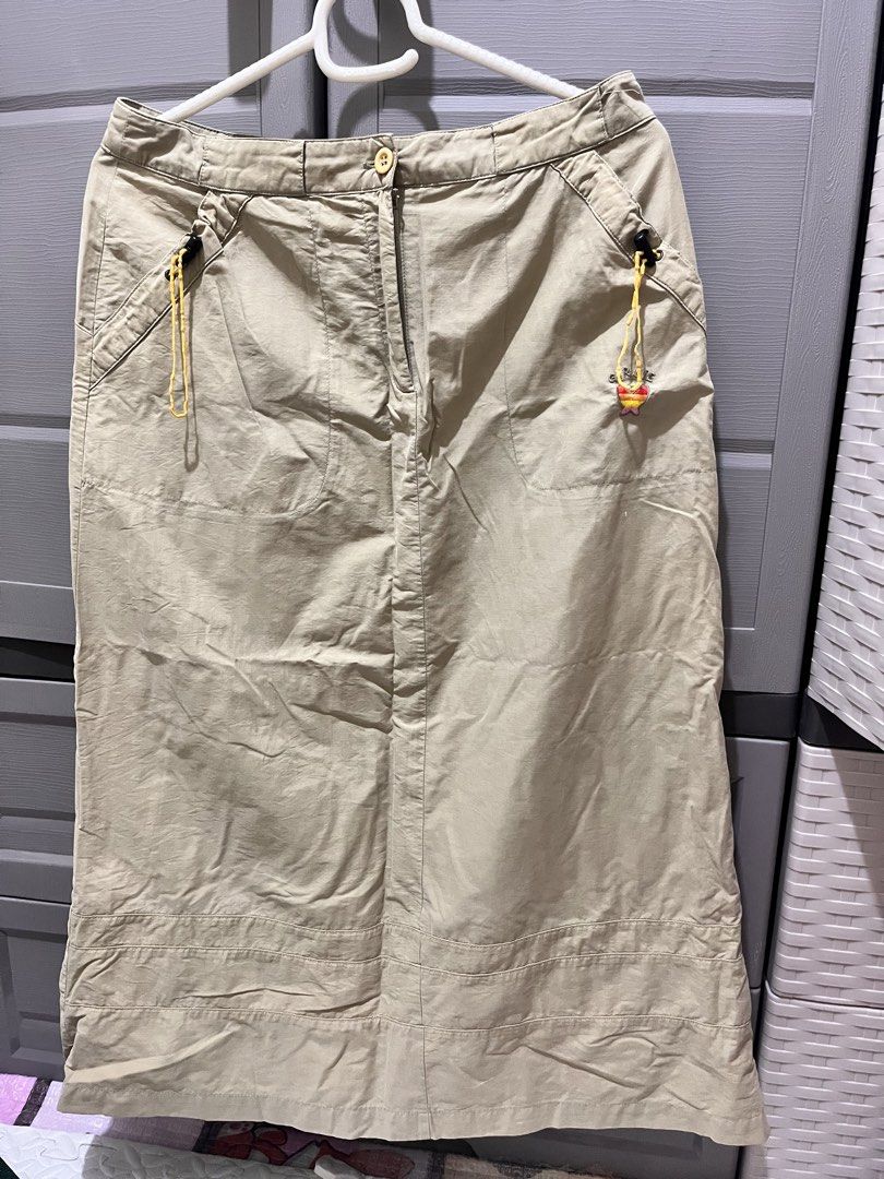 Khaki Utility Midi Skirt (Category: Skirts) located in Taguig. Submitted by notyoursam (Listing ID 1469690488, Image 1). Description: - Color: Versatile khaki earthy tone - Material: Comfortable cotton blend - Closure: Front button with zipper fly - Pockets: Two angled front pockets with yellow drawstring cords and toggle adjusters - Cute Detail: Small colorful heart charm on the left pocket - Design: Panel stitching near the hemline with a strai
