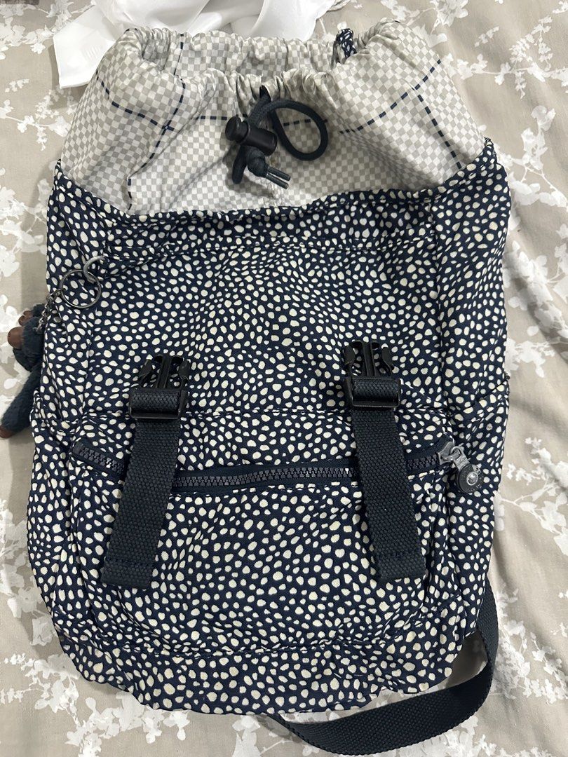Kipling Navy White Polka Dot Backpack (Category: Backpacks) located in Quezon City. Submitted by _samanthajyc (Listing ID 1469714111, Image 3). Description: Navy and white polka dot backpack from Kipling. Drawstring top closure under the flap with buckle straps. Front zip pocket and adjustable black shoulder straps. Inside lined with a grey checked pattern and includes a slip pocket. Some tarnishing on the metal buckles..
