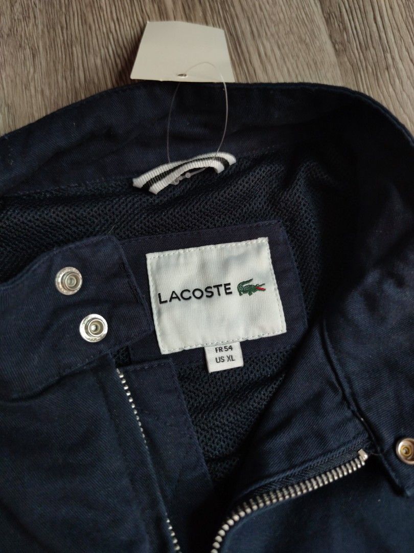 Lacoste Harrington Navy Blue Jacket BH3921 (Category: Coats, Jackets and Outerwear) located in Pasig City. Submitted by vintage.thrifttph (Listing ID 1469651752, Image 2). Description: - Brand: Lacoste - Style Number: BH3921 - Condition: Used 9/10 condition - Color: Solid Navy - Size: 23 width 25 length (boxy fit) - Details: Full zip front, mock collar with snap buttons, comfortable mesh lining, ribbed cuffs and hem - Features the iconic Lacoste 