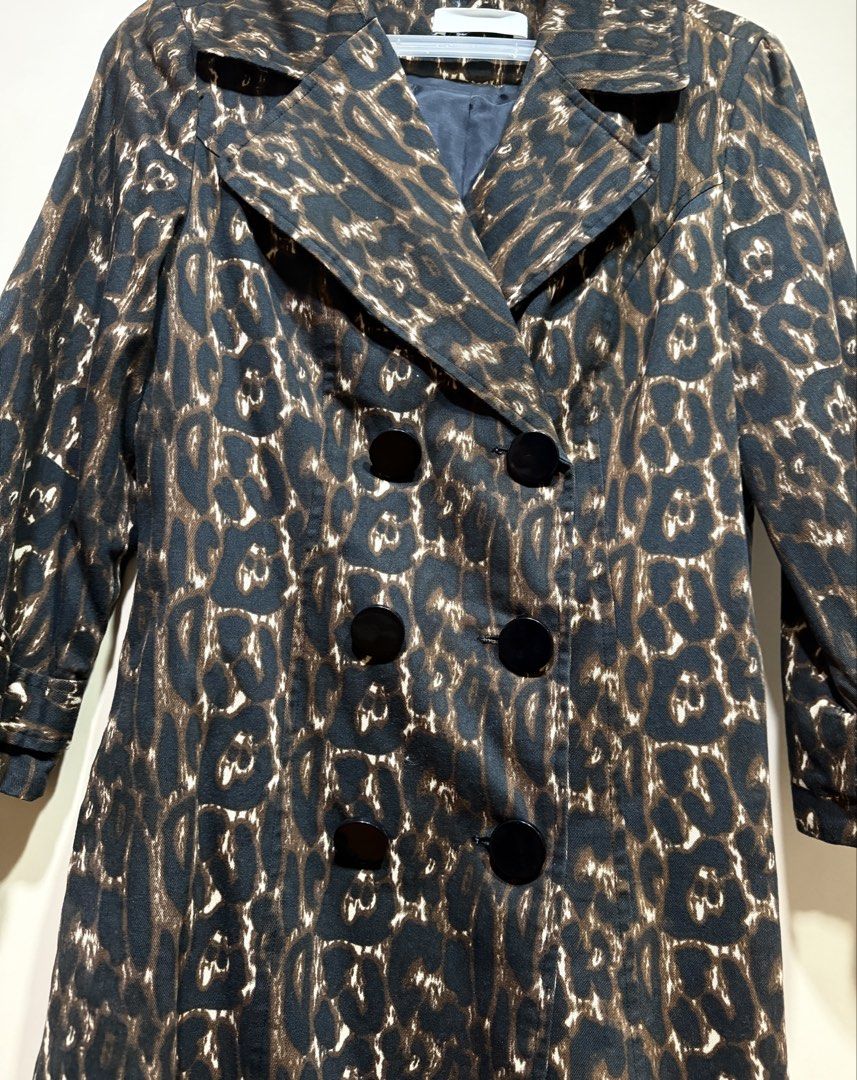 Leopard Print Trench Coat (Category: Coats, Jackets and Outerwear) located in Muntinlupa City. Submitted by caroucella (Listing ID 1469634537, Image 2). Description: Leopard print trench coat with black buttons down the front. Lapel collar and structured shoulders. Back includes a decorative half-belt flap detail with two black buttons. Dark lining inside. Catchy animal print pattern all over. Super stylish.