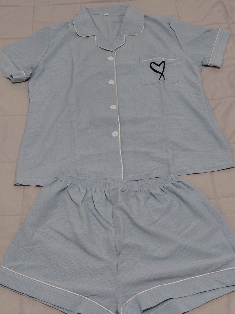 Light blue checkered pyjamas short sleeve set with heart pocket (Category: Sets or Coordinates) located in Taguig. Submitted by ynelshop (Listing ID 1469690216, Image 1). Description: - Color: Light blue with subtle checkered pattern - Set includes: Short-sleeve button-up top and matching shorts - Details: White piping trim, chest pocket with cute black embroidered heart - Waistband: Comfortable elastic waistband - Material: Soft fabric ideal for