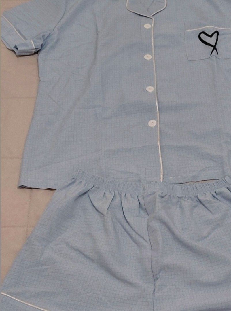 Light blue checkered pyjamas short sleeve set with heart pocket (Category: Sets or Coordinates) located in Taguig. Submitted by ynelshop (Listing ID 1469690216, Image 2). Description: - Color: Light blue with subtle checkered pattern - Set includes: Short-sleeve button-up top and matching shorts - Details: White piping trim, chest pocket with cute black embroidered heart - Waistband: Comfortable elastic waistband - Material: Soft fabric ideal for