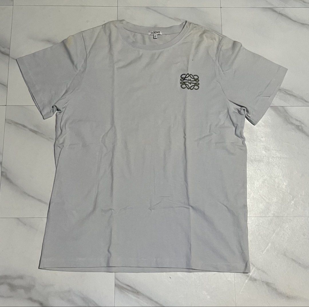 Loewe T-shirt with Anagram Logo (Category: Shirts) located in Cavite. Submitted by christianzuuu (Listing ID 1469739982, Image 1). Description: - Brand: Loewe - Color: Light grey - Material: 100% cotton - Details: Small embroidered Anagram logo on chest, crew neck, short sleeves, standard fit - Size/Measurements (Flat Lay): Length ~26.5 inches, Width ~21 inches - Condition: Clean overall, with a minor yellowish stain near the right shoulder area.