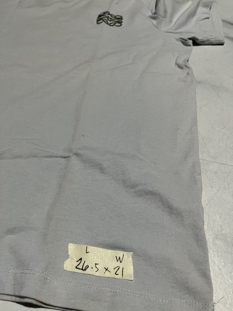 Loewe T-shirt with Anagram Logo (Category: Shirts) located in Cavite. Submitted by christianzuuu (Listing ID 1469739982, Image 2). Description: - Brand: Loewe - Color: Light grey - Material: 100% cotton - Details: Small embroidered Anagram logo on chest, crew neck, short sleeves, standard fit - Size/Measurements (Flat Lay): Length ~26.5 inches, Width ~21 inches - Condition: Clean overall, with a minor yellowish stain near the right shoulder area.