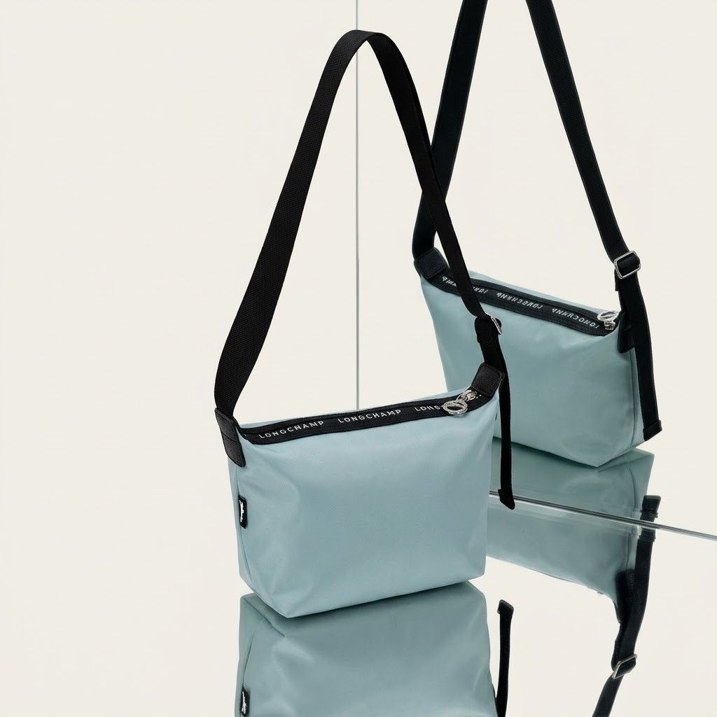 Longchamp Crossbody Bag Light Blue (Category: Cross-body Bags) located in Carmen. Submitted by ar_thrift00 (Listing ID 1469636664, Image 1). Description: - Longchamp crossbody bag in a chic light blue shade - Durable and lightweight clean nylon material, ideal for daily use - Comfortable black adjustable strap for custom fit - Silver-tone zipper pull stamped with the iconic logo - Features a small horse logo patch on the side - Interior fabric li