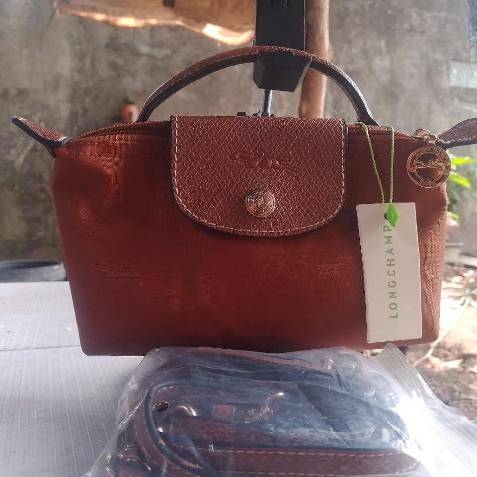 Longchamp Le Pliage Cuir Pouch Brown (Category: Luxury Bags & Wallets) located in Muntinlupa City. Submitted by armendaber03743 (Listing ID 1469636950, Image 1). Description: - Authentic Longchamp pouch in a stylish rich brown nylon - Features a structured top flap with a secure gold snap closure - Secure zippered main compartment for your essentials - Interior tag reads: Longchamp Paris, Made in Tunisia - Includes a brand new, detachable shoulde
