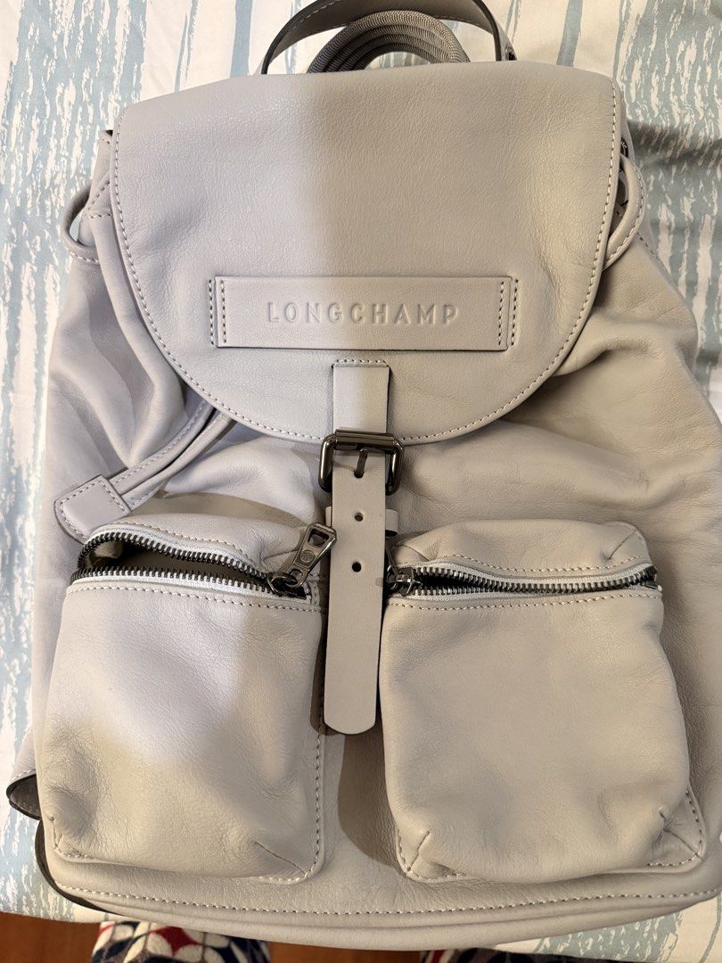 Longchamp Leather Backpack Grey (Category: Backpacks) located in Manila. Submitted by mitch_gnz (Listing ID 1469757936, Image 1). Description: - Authentic Longchamp leather backpack in elegant light grey - Secure front flap with buckle closure and drawstring top opening - Two convenient zipped external pockets for easy access - Spacious fabric-lined interior with built-in compartments - Comfortable, thick webbing shoulder straps on the back - Cle