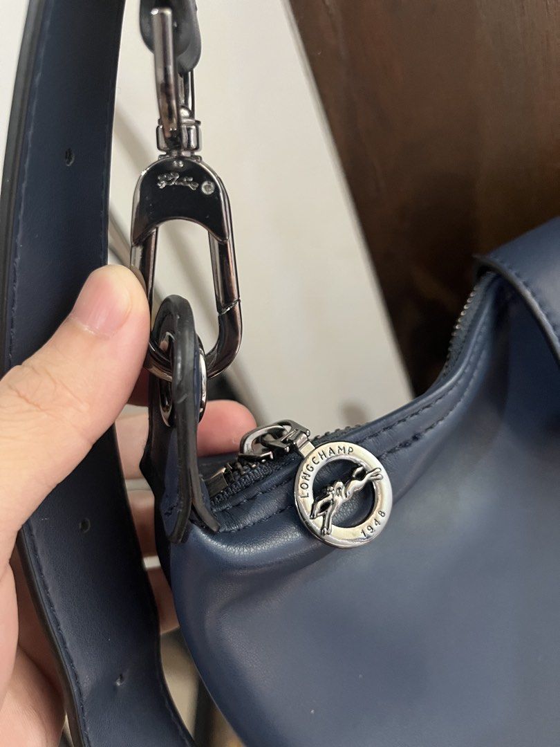 Longchamp Navy Leather Shoulder Bag (Category: Luxury Bags & Wallets) located in Mabalacat. Submitted by onlygrail.pamp (Listing ID 1469634277, Image 3). Description: - Brand: Longchamp - Color: Navy blue - Material: Premium leather - Closure: Secure top zip with branded metal pull - Front Detail: Embossed logo flap with snap button - Strap: Adjustable matching strap with silver-toned hardware rings - Condition: Sturdy construction, clean, and id