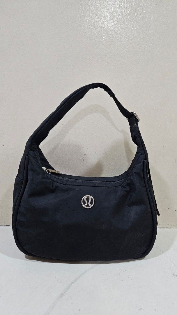Lululemon Black Nylon Shoulder Bag (Category: Shoulder Bags) located in Paranaque City. Submitted by babythings (Listing ID 1469677696, Image 1). Description: - Brand: Lululemon - Color: Classic Black - Material: 100% recycled nylon (body and lining) - Closure: Secure zip closure for the main compartment - Pockets: Exterior zipped pocket on the back for easy access - Hardware: Silver-tone hardware with an adjustable strap - Details: Iconic Lulule