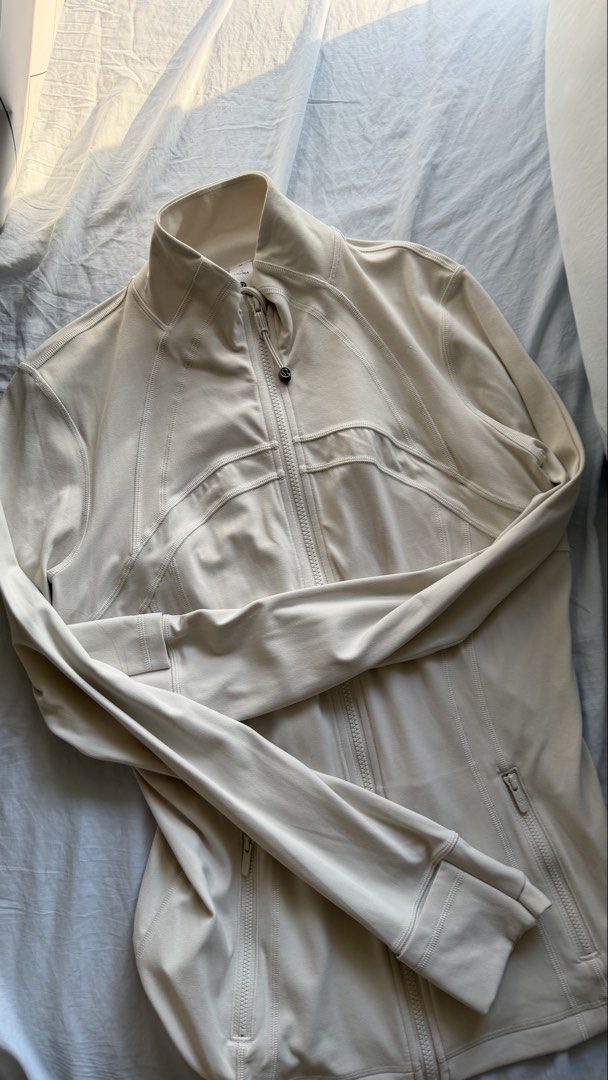 Lululemon Define Jacket Cream White Size 10 (Category: Coats, Jackets and Outerwear) located in Mandaluyong City. Submitted by tidyingupnow (Listing ID 1469652300, Image 1). Description: - Brand: Lululemon Define Jacket - Color: Cream / Off-White - Size: 10 (tag intact near collar) - Features: Full zip front, high neckline, thumbholes at cuffs - Pockets: Secure zippered pockets on both sides - Details: Breathable fabric panels on the back and ref