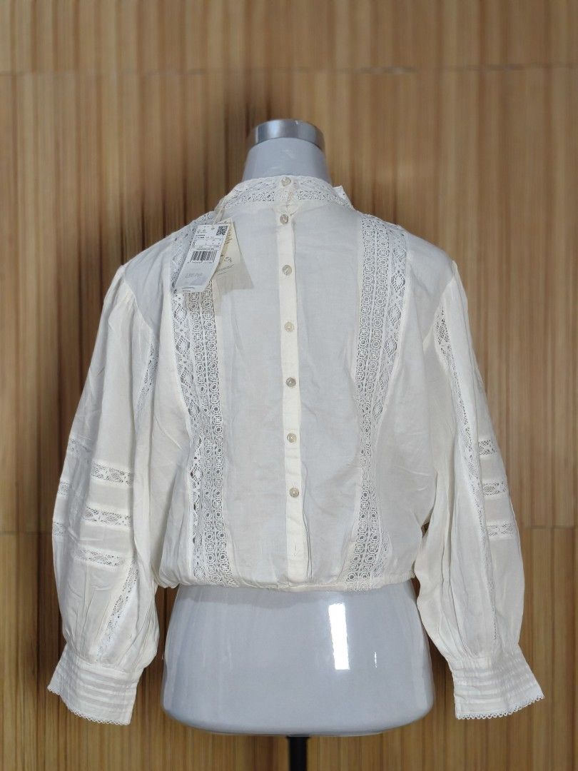 Mango White Lace Detailed Blouse (Category: Blouses) located in Taguig. Submitted by ashie_clothing (Listing ID 1469678922, Image 3). Description: - Brand: Mango - Color: White - Material: Soft, lightweight cotton - Design: Intricate lace panels, high mock neckline, and long balloon sleeves with lace inserts and cuffed wrists - Closure: Full back button-down - Condition: Brand new with original retail tag attached.