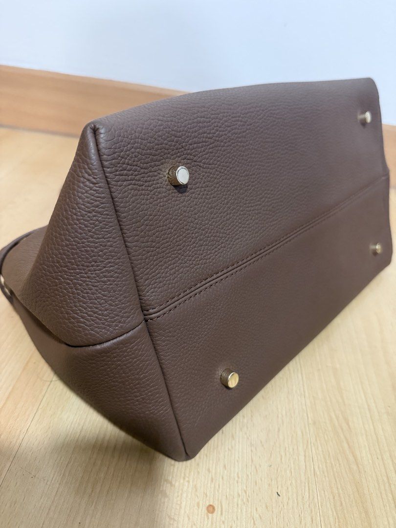 Manu Atelier Brown Leather Tote Bag (Category: Tote Bags) located in Makati City. Submitted by dgcurated09 (Listing ID 1469735988, Image 3). Description: - Brand: Manu Atelier - Material: Premium brown pebbled leather - Design: Structured tote with twin top handles and gold-stamped logo - Details: Decorative buckled strap wrapping around front and back, with protective metal feet underneath - Perfect for daily use, work, or casual outings .