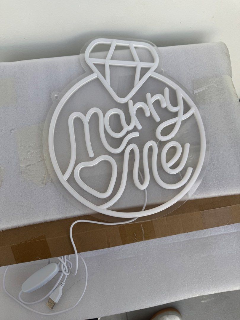 Marry Me Ring LED Neon Sign Light Proposal Decor (Category: Other Home Appliances) located in Las Pinas. Submitted by sportyyyyy (Listing ID 1469689817, Image 3). Description: - Design: "Marry Me" text with a cute heart at the bottom and a diamond on top - Backing: Clear acrylic for a clean, floating look - Power: USB powered with a convenient inline switch on the white cord - Versatile: Ideal for marriage proposals, engagement parties, and roman