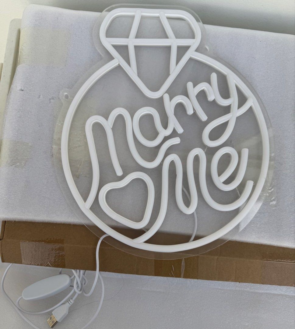 Marry Me Ring LED Neon Sign Light Proposal Decor (Category: Other Home Appliances) located in Las Pinas. Submitted by sportyyyyy (Listing ID 1469689817, Image 2). Description: - Design: "Marry Me" text with a cute heart at the bottom and a diamond on top - Backing: Clear acrylic for a clean, floating look - Power: USB powered with a convenient inline switch on the white cord - Versatile: Ideal for marriage proposals, engagement parties, and roman