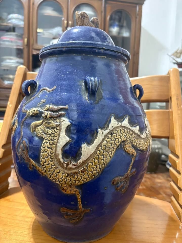 martaban Blue glazed ceramic storage jar with dragon relief (Category: Vases & Decorative Bowls) located in Alfonso. Submitted by luckyfire_80773d (Listing ID 1469593706, Image 1). Description: - Deep blue glazed ceramic jar with matching lid - Intricately sculpted dragon wrapped around the body with detailed scales and claws - Accentuated with earthy tones and small decorative loop handles - Authentic unglazed coarse clay base showing natural we