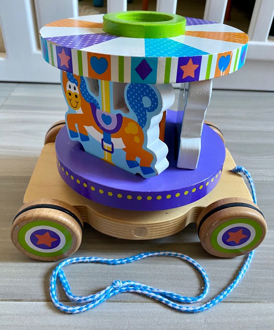 Melissa & Doug Carousel Pull toy (RARE) (Category: Kids Toys) located in Bauang. Submitted by tinyhandspreloved (Listing ID 1469594943, Image 1). Description: - Brand: Melissa & Doug First Play - Recommended Age: 18 months and up - Features: Rolling wooden base with pull string, rotating striped top, and purple platform with slots - Activity: Match the 3 colorful horse puzzle pieces into the slots - Benefits: Promotes early motor skills and hand-