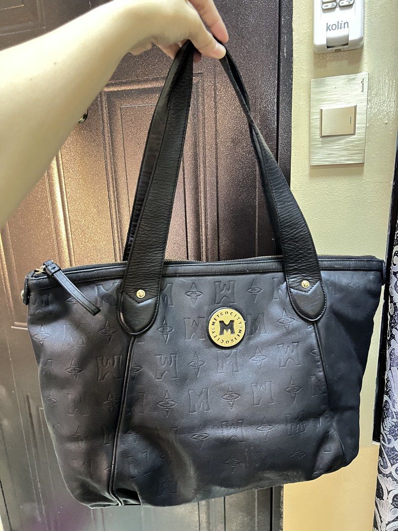 Metrocity Black Leather Monogram Tote Bag (Category: Tote Bags) located in Manila. Submitted by colineb (Listing ID 1469669088, Image 2). Description: - Brand: Metrocity - Material: Premium black leather with debossed monogram pattern - Hardware: Elegant gold-tone hardware and front logo emblem - Closure: Secure zip-top closure - Straps: Comfortable double shoulder straps with stud details - Interior: Fabric-lined with a convenient zippered pocke