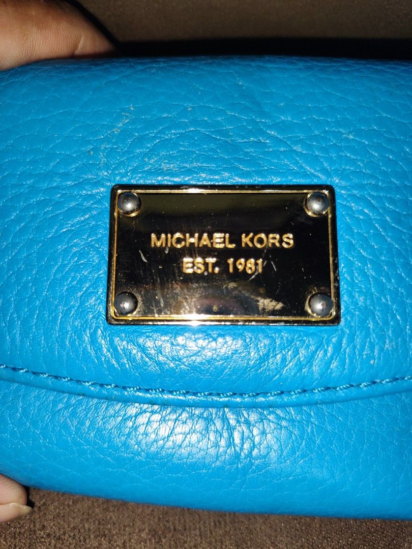 Michael Kors Blue Leather Wallet (Category: Wallets & Card holders) located in Paniqui. Submitted by arlenepari29210 (Listing ID 1469709447, Image 2). Description: - Authentic Michael Kors pebbled leather wallet in a vibrant bright blue - Elegant gold-tone nameplate hardware on the front flap - Secure snap closure leading to multiple card slots, slip pockets, and a zippered coin compartment - Signature MK logo fabric interior lining - Condition: 