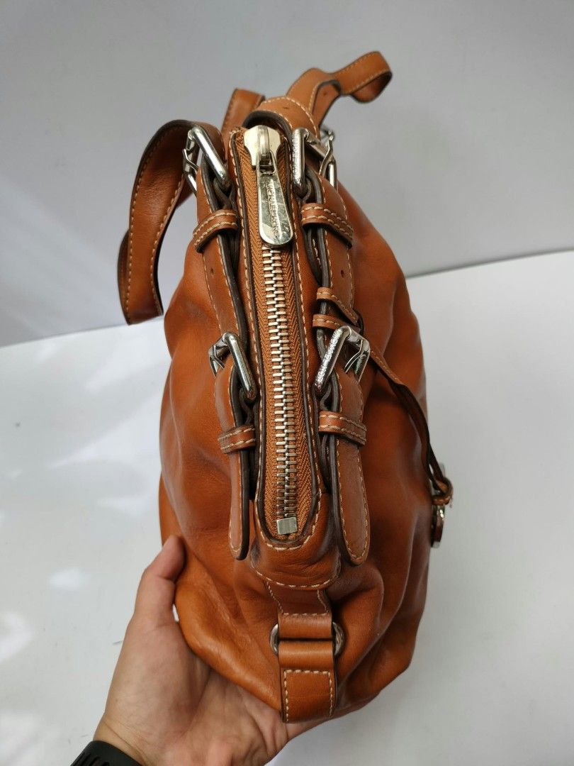 Michael Kors brown leather shoulder bag with studs (Category: Luxury Bags & Wallets) located in Baguio. Submitted by galdzz_23 (Listing ID 1469661313, Image 2). Description: - Authentic Michael Kors shoulder bag in rich tan brown leather - Stylish double vertical rows of metal studs on the front - Sleek silver-tone hardware with adjustable buckle straps - Includes signature hanging MK charm - Secure zip top closure - Spacious interior with a soft