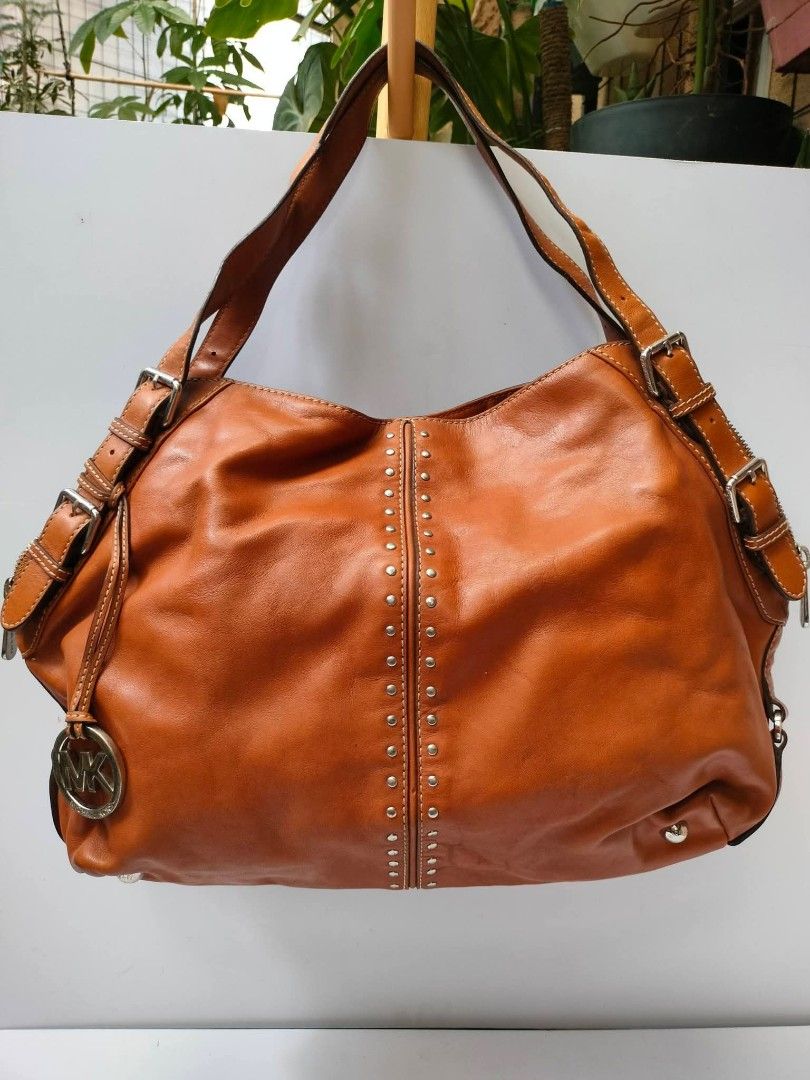 Michael Kors brown leather shoulder bag with studs (Category: Luxury Bags & Wallets) located in Baguio. Submitted by galdzz_23 (Listing ID 1469661313, Image 1). Description: - Authentic Michael Kors shoulder bag in rich tan brown leather - Stylish double vertical rows of metal studs on the front - Sleek silver-tone hardware with adjustable buckle straps - Includes signature hanging MK charm - Secure zip top closure - Spacious interior with a soft