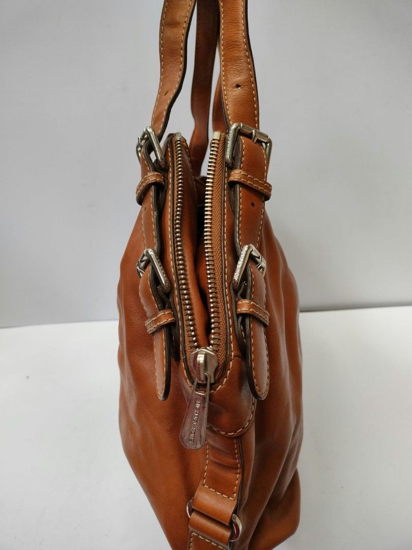 Michael Kors brown leather shoulder bag with studs (Category: Luxury Bags & Wallets) located in Baguio. Submitted by galdzz_23 (Listing ID 1469661313, Image 3). Description: - Authentic Michael Kors shoulder bag in rich tan brown leather - Stylish double vertical rows of metal studs on the front - Sleek silver-tone hardware with adjustable buckle straps - Includes signature hanging MK charm - Secure zip top closure - Spacious interior with a soft