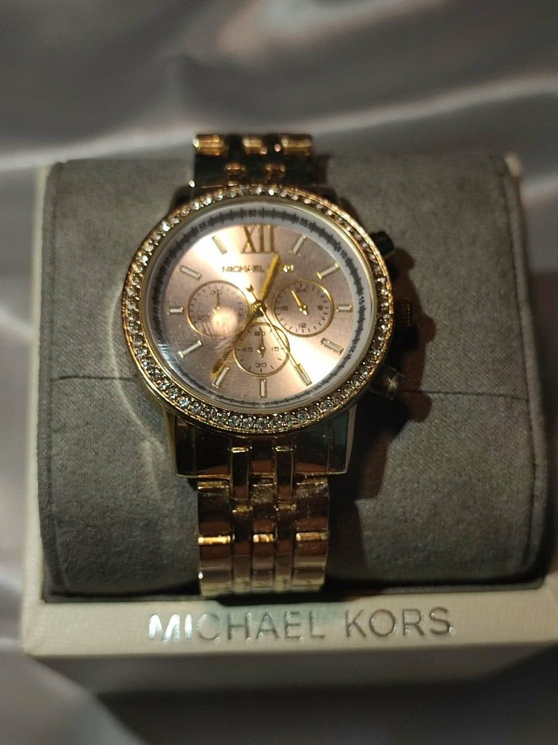Michael Kors Gold Watch Bundle Set (Category: Women's Watches) located in Manila. Submitted by aki_fujiko03 (Listing ID 1469623084, Image 2). Description: - Watch 1: Sleek square face with a sophisticated dark dial - Watch 2: Round chronograph piece with sparkling crystal stones on the bezel - Both feature matching elegant gold-tone metal link bracelets - Includes original Michael Kors presentation box - Great value bundle, perfect for gifting or
