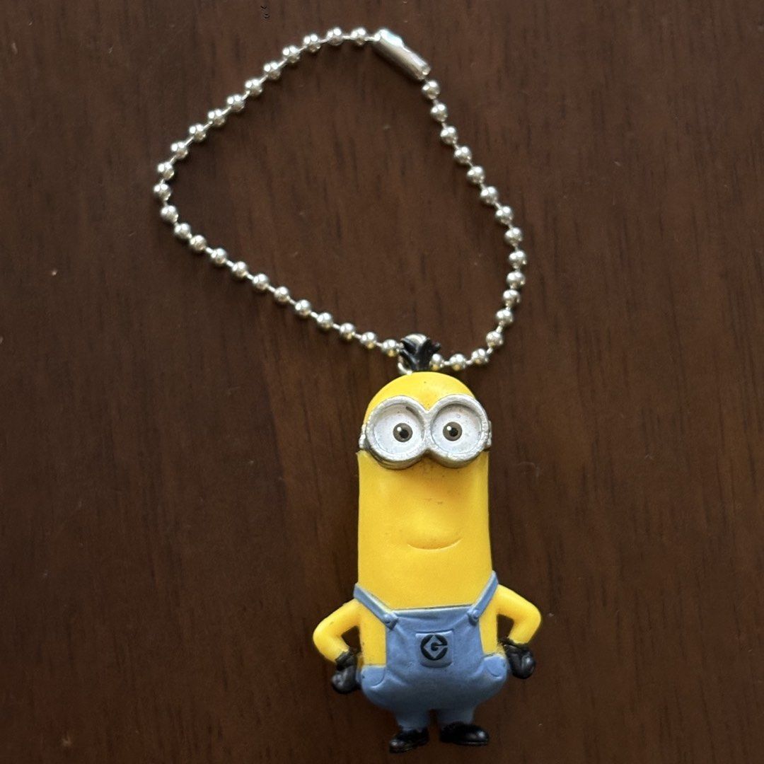 Minion Keychain (Category: Character Goods) located in Manila. Submitted by aobacafe (Listing ID 1469678985, Image 1). Description: - Adorable yellow Minion figurine keychain - Iconic blue overalls design featuring the 'G' logo - Made of durable, high-quality rubber material - Includes a sturdy silver ball chain for easy attachment - Standard size, perfect for keys, bags, or lanyards.