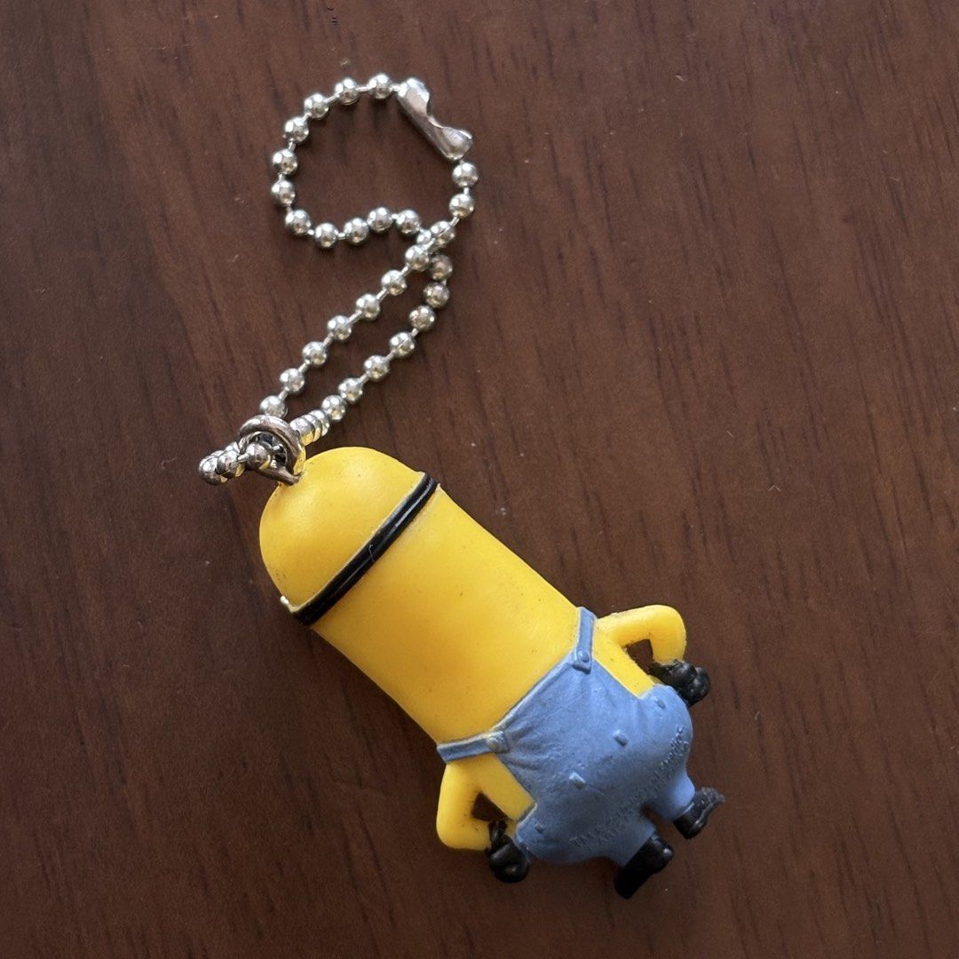 Minion Keychain (Category: Character Goods) located in Manila. Submitted by aobacafe (Listing ID 1469678985, Image 2). Description: - Adorable yellow Minion figurine keychain - Iconic blue overalls design featuring the 'G' logo - Made of durable, high-quality rubber material - Includes a sturdy silver ball chain for easy attachment - Standard size, perfect for keys, bags, or lanyards.