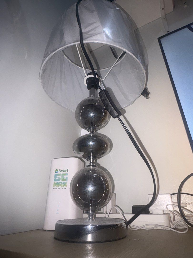 Modern Table Lamp with Stacked Glass Spheres (Category: Lighting) located in Manila. Submitted by rodriguesyb (Listing ID 1469638249, Image 3). Description: - Elegant design featuring 3 stacked smoked glass spheres - Sturdy chrome base with a flat, round stand - Topped with a white fabric shade (protective plastic wrap still attached) - Convenient black power cord with an inline toggle switch - Perfect size for bedside nightstands or office desk 