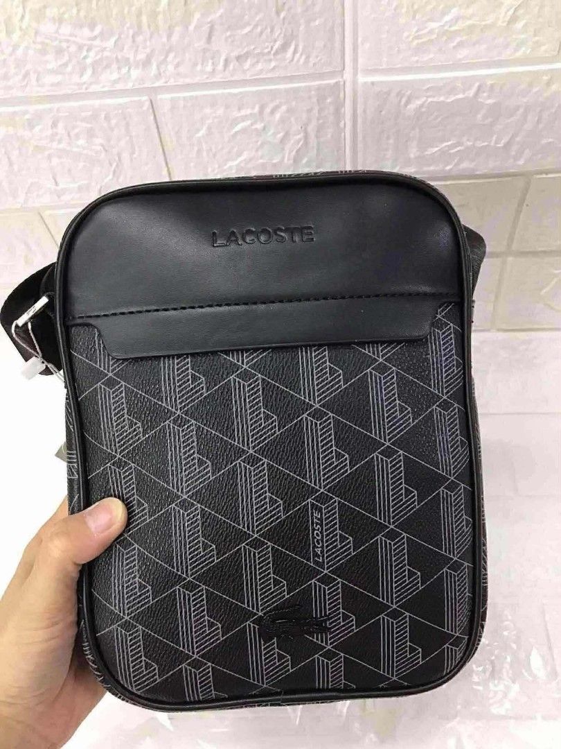 Monogram Print Crossbody Bag Black (Category: Sling Bags) located in Manila. Submitted by prime.dlor (Listing ID 1469743106, Image 1). Description: - Authentic Lacoste crossbody bag in black - Features a stylish geometric monogram pattern with smooth leather top panel - Silver-tone hardware with iconic embossed branding and tiny crocodile zipper pull - Adjustable black shoulder strap for comfortable wear - Includes original white dust bag and pap