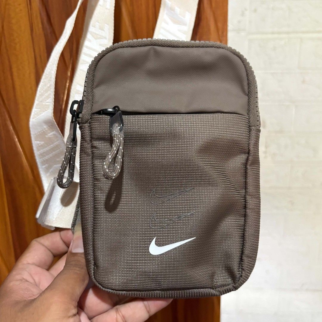 Nike Crossbody Bag Brown (Category: Belt bags, Clutches and Pouches) located in Carmen. Submitted by ar_thrift00 (Listing ID 1469635136, Image 2). Description: - Brand: Nike - Color: Brown with adjustable white logo strap - Material: Durable canvas - Storage: Main compartment with mesh inner pocket + front zippered pocket - Closure: Quick-release buckle - Condition: Clean inside and out, ready to use - Perfect for: Carrying daily essentials, phon
