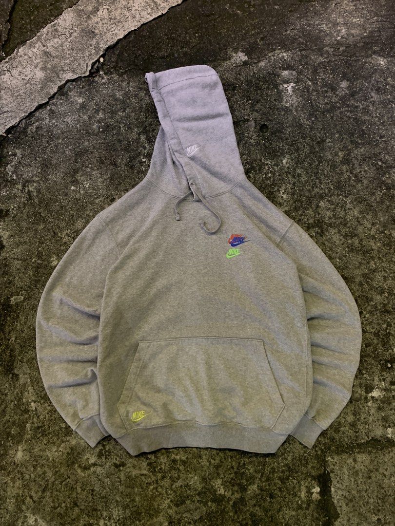 Nike Grey Multiple Logo Embroidered Pullover Hoodie (Category: Hoodies) located in Manila. Submitted by thrift2mnla (Listing ID 1469681243, Image 1). Description: Grey Nike hoodie with stacked multi-color embroidered logos on the chest, a white logo hit on the hood, and a lime green swoosh near the pocket hem. Standard drawstring hood and front pouch pocket. Heavyweight cotton fleece material, comfortable fit..