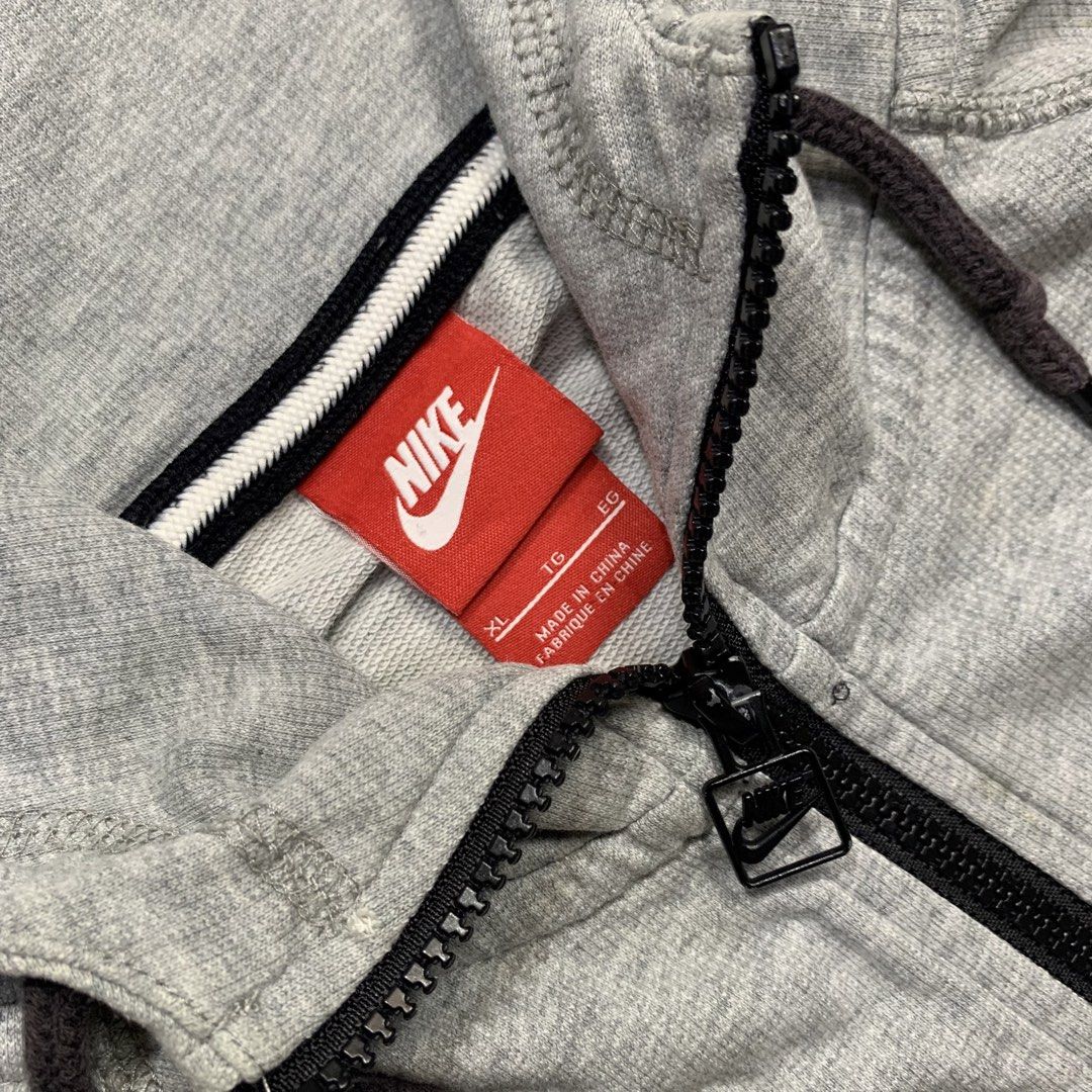 Nike Grey Zip-Up Hoodie (Category: Hoodies) located in Kalibo. Submitted by gneiss2002 (Listing ID 1469695697, Image 2). Description: - Authentic grey Nike zip-up hoodie - Material: Comfortable cotton with regular fit - Design: Full front zipper and adjustable drawstring hood - Branding: White embroidered Nike logo on the left chest - Storage: Two front pockets plus a secure zippered pocket on the left sleeve - Details: Ribbed cuffs for a snug fi