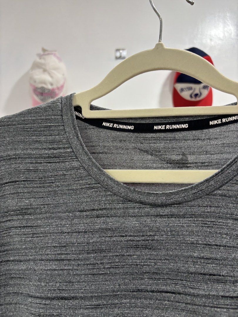 Nike Running Gray Heather Athletic T-Shirt (Category: Activewear) located in Calbayog City. Submitted by zaxcheus_castillo1708 (Listing ID 1469672427, Image 2). Description: - Brand: Nike - Color: Gray Heather (marled texture) - Style: Crew neck with branded inner taping, short sleeves - Fit: Curved hem at the back for extra workout coverage - Material: Lightweight, breathable athletic fabric - Condition: Excellent, ready to wear.