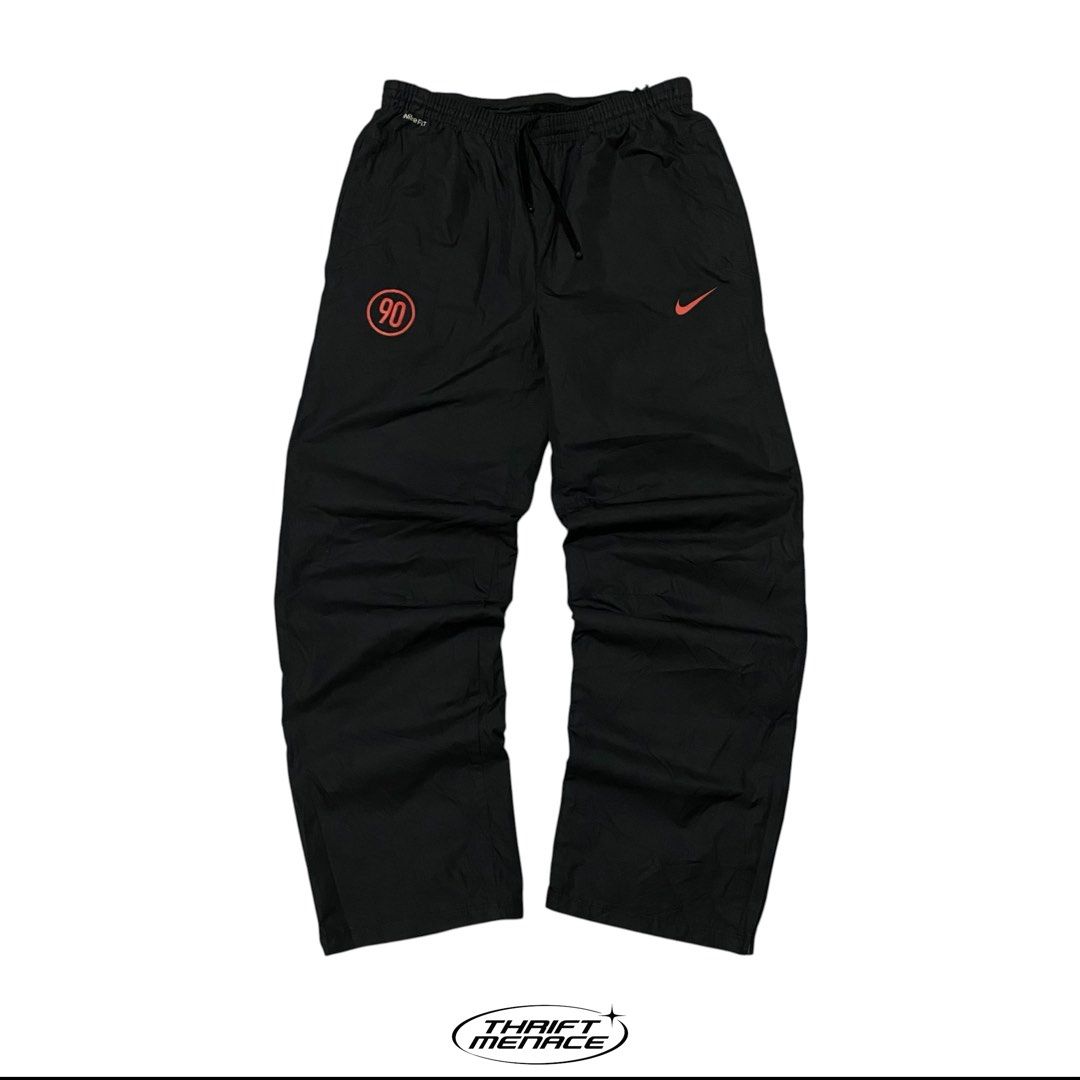 Nike Total 90 Black Track Pants (Category: Joggers) located in Manila. Submitted by urboycee (Listing ID 1469711280, Image 1). Description: - Brand: Nike Total 90 - Color: Black with orange accents - Size: Medium (M tag inside) - Features: Nike Fit Storm technology, adjustable drawstring waist, lower leg zippers - Branding: Printed T90 logo near waistband, small Swoosh and '90' graphic on front leg - Condition: Clean overall, well-maintained.