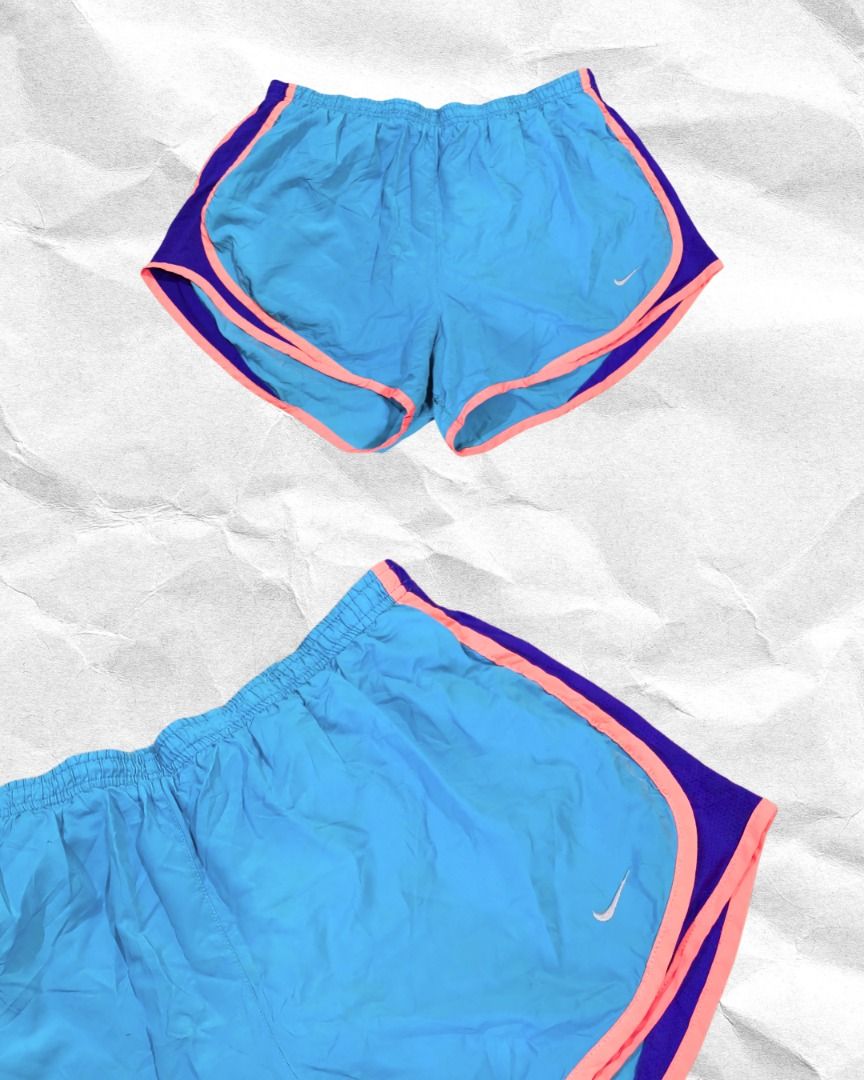 Nike Tri Color Running Shorts (Category: Shorts) located in Mandaluyong City. Submitted by juliaaaaaannnn (Listing ID 1469681681, Image 1). Description: - Dimensions: (L) 30x13 - Color: Bright blue with purple side panels and pink contrast piping - Features: Elastic waistband with drawstring, small white Nike swoosh on left hem - Material: Super lightweight - Best for: Running, workouts, and gym sessions.