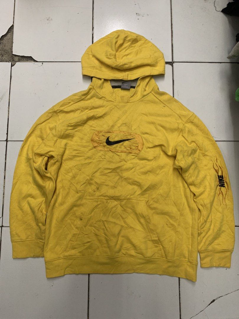Nike Yellow Flame Graphic Hoodie (Category: Hoodies) located in Tarlac. Submitted by luxurious_apparel (Listing ID 1469658069, Image 1). Description: - Brand: Nike - Style: Bright yellow hoodie with front kangaroo pocket - Size: XL - Origin: Made in Malaysia - Design details: Black swoosh inside an embroidered flame patch on the chest, plus matching flame graphics and Nike lettering on the left sleeve - Condition: Shows visible dirt stains and di