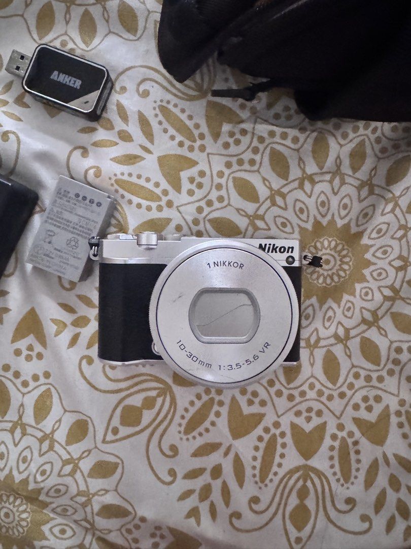 Nikon 1 J5 Mirrorless Camera with 10-30mm Lens (Category: Cameras) located in Carmen. Submitted by t1torref (Listing ID 1469593615, Image 3). Description: - one flaw: minor dent in front as seen in photo -Model: Nikon 1 J5 Mirrorless Camera (Silver & Black) - Lens: 10-30mm VR lens with clean optics - Condition: Powers on, fully tested, and working properly - Inclusions: Original battery, spare battery, external battery charger, 32 gb micro sd car