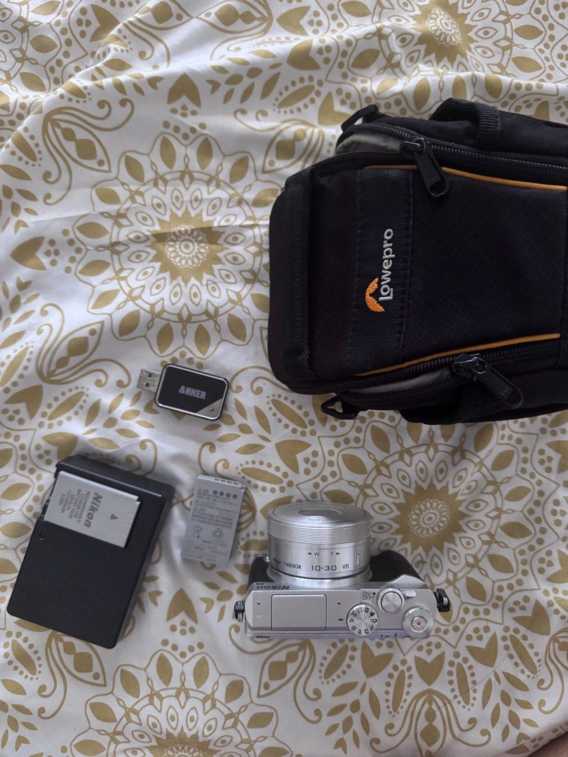Nikon 1 J5 Mirrorless Camera with 10-30mm Lens (Category: Cameras) located in Carmen. Submitted by t1torref (Listing ID 1469593615, Image 1). Description: - one flaw: minor dent in front as seen in photo -Model: Nikon 1 J5 Mirrorless Camera (Silver & Black) - Lens: 10-30mm VR lens with clean optics - Condition: Powers on, fully tested, and working properly - Inclusions: Original battery, spare battery, external battery charger, 32 gb micro sd car