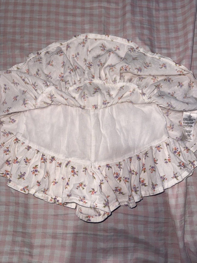 Old Navy Floral Ruffle Skort Size 4T (Category: Babies & Kids Fashion) located in Marikina City. Submitted by mvmaggie (Listing ID 1469587084, Image 2). Description: - Brand: Old Navy - Size: 4T - Design: White with small purple and pink floral print - Features: Easy elastic waistband, built-in shorts, and layered ruffle skirt design - Material: Shell (55% cotton, 45% rayon), Lining (100% cotton) - Care: Machine washable - Condition: Great for pl