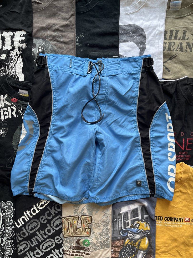 OP Boardriding Team Blue Black Surf Shorts (Category: Swim Trunks & Board Shorts) located in Baao. Submitted by plainclothesdept (Listing ID 1469696903, Image 1). Description: y2k OP blue boardshorts waist - 32-34 in. length - 20 in. hem - 12 in. no flaws - Brand: OP Boardriding Team - Color: Light blue and black - Material: Smooth, quick-drying synthetic fabric - Features: White text branding on side leg, graphic circular logo on pocket flap - C