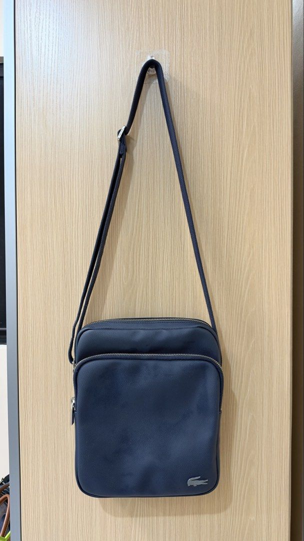 Original Lacoste Navy Blue Crossbody Bag (Category: Sling Bags) located in Quezon City. Submitted by declutterw_v (Listing ID 1469677145, Image 1). Description: Navy blue Lacoste crossbody bag. Structured texture finish with a silver metal crocodile logo on the lower front corner. Adjustable shoulder strap attached. Front zip pocket plus main zipped compartment. Interior lined in matching navy fabric with a zippered pocket and Lacoste branded pat